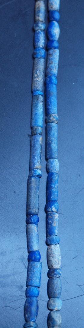 古代濃紺ラピスの管玉や丸玉をほぼ左右対称に編み、トップに斧型や多面体、80個の連